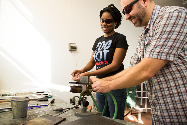 Jim showing UncommonGoods Tabletop Buyer NeQuana the torch