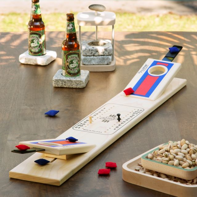 Tabletop cornhole game with stone coasters and a pistachio pedestal